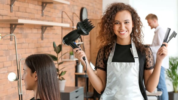 Mulher profissional da beleza segurando um secador na mão direita e pente na mão esquerda